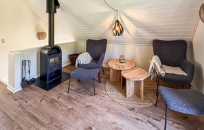 A cozy room with a wood-burning stove, two armchairs, a round wooden table, and a hanging light fixture. - Pet friendly home in Gråsten with sauna (Gråsten)