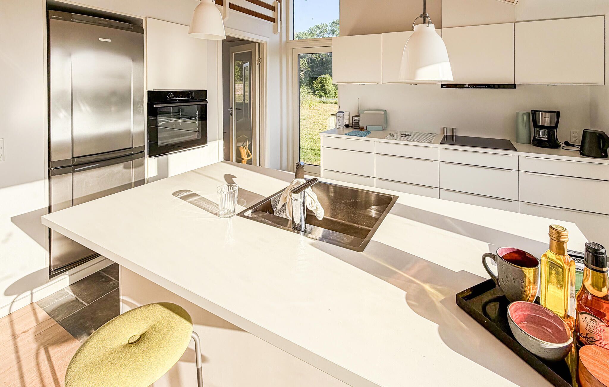 A modern kitchen with a central island, stainless steel appliances, and a view of the outdoors.