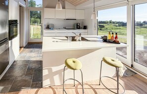 Une cuisine moderne dotée d’un grand îlot central, d’un évier et de tabourets de bar.