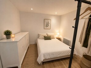 A bedroom with a bed, bedside table, lamp, potted plant, and a hanging coat rack. - A cozy vacation home with a terrace (PYLA SUR MER)