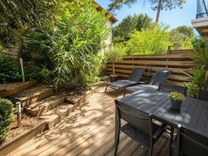 A wooden deck with built-in planters, a table, and two lounge chairs. - A cozy vacation home with a terrace (PYLA SUR MER)
