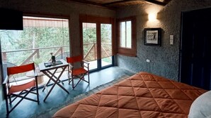 Een kamer met een bed, een tafel, stoelen en een balkon met uitzicht.