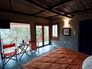Ein Zimmer mit einem Bett, einem Tisch, Stühlen und einem Balkon mit Blick.