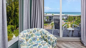 A balcony with a view of the ocean, a chair, and a table. - Treasure Island Gulf Front Condo Ocean Views (Treasure Island)