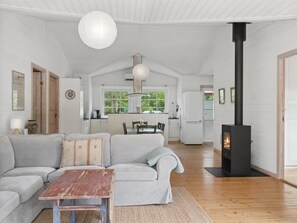 Ein geräumiger Wohnbereich mit einer Couch, einem Holztisch und einem schwarzen Kamin.