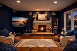 Una sala de estar con chimenea, televisor y estantería.