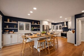 Una cocina moderna con una isla central, taburetes de madera y electrodomésticos integrados.