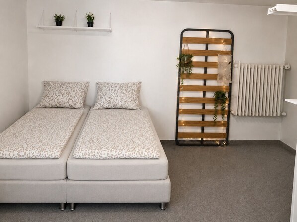 A room with a double bed, a radiator, a shelf with plants, and a decorative wooden panel with lights. - Studio in the heart of Reykjavík Perfect for your stay (Reykjavík)