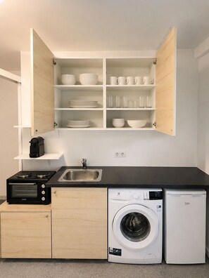 Una cocina compacta con horno integrado, lavadora y lavaplatos.