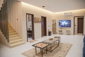 Een moderne woonkamer met een flatscreen-televisie, een trap en een eethoek.