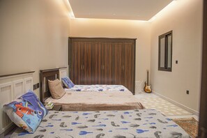 Een slaapkamer met twee bedden, een kledingkast, een gitaar en een kamerkleed met dessin.