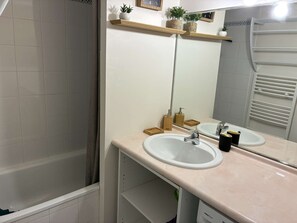 Een badkamer met twee wastafels, een spiegel, een douche en een handdoekrek.