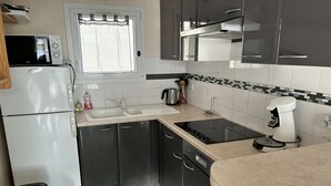Eine kleine Küche mit Kühlschrank, Mikrowelle, Spüle, Herd und Kaffeemaschine.