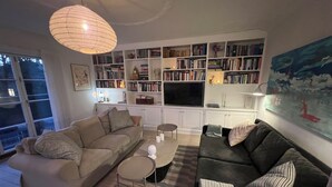 Un saló amb un sofà, una taula de centre, una prestatgeria, una televisió de pantalla plana i un quadre a la paret.