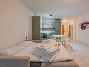 A modern hotel room with a bed, a small kitchenette, a dining area, and a bathroom. - Apartment Nala by Interhome (Riva del Garda)