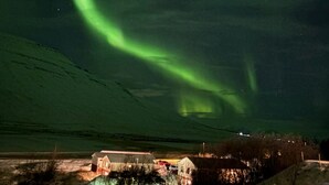 A building with a sloped roof, a visible road, and a snow-covered ground. - Kosy 1-bedroom apartment in enjoyable Hólar for your stay (Hólar)