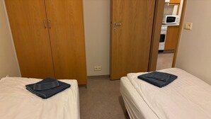 A room with two beds, wooden wardrobes, and a kitchenette in the background. - Kosy 1-bedroom apartment in enjoyable Hólar for your stay (Hólar)