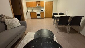A compact living space with a sofa, dining table, chairs, a kitchen area with cabinets and appliances, and a small black table. - Kosy 1-bedroom apartment in enjoyable Hólar for your stay (Hólar)