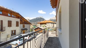 A balcony with a view of a mountain, a white car parked in front, and a building with wooden shutters. - Le Jovet - AIME LA PLAGNE (AIME LA PLAGNE)