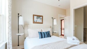 A neatly made bed with a quilted blanket, two pillows, and a folded towel on the side. There is a framed picture on the wall above the bed. - Red Bud Suite (Staunton)
