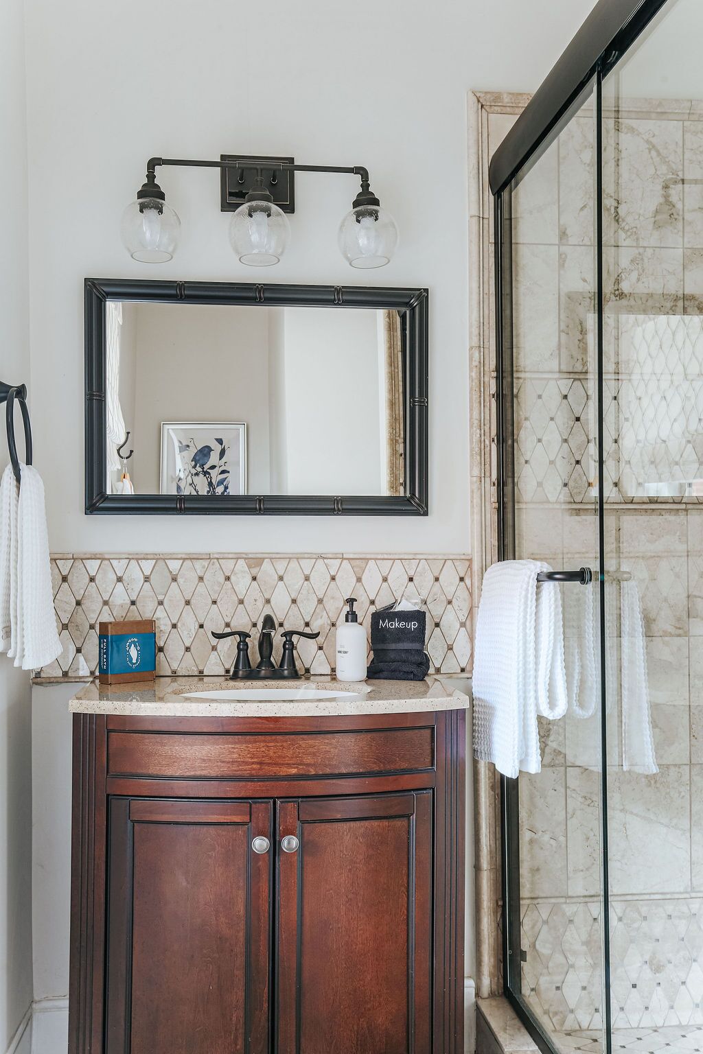 A bathroom with a wooden vanity, a large mirror, and a shower area.