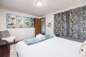 Un dormitorio con cama, una silla, una puerta y decoración en la pared.