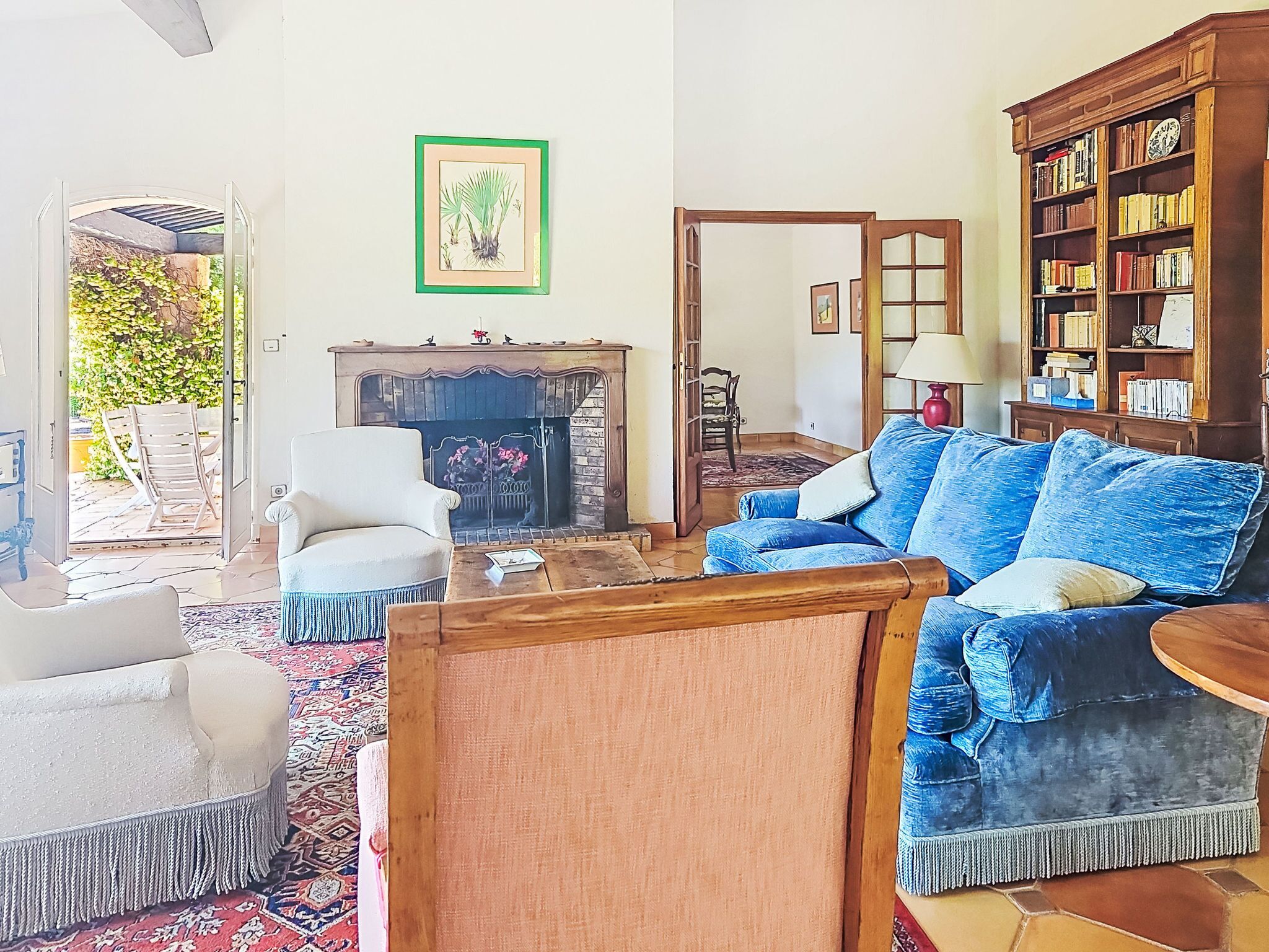 A living room with a fireplace, a sofa, a chair, a bookshelf, and a framed picture on the wall.