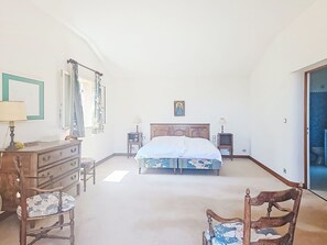 Een slaapkamer met een bed, een dressoir, een stoel, een nachtkastje en een televisietoestel.