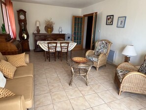 Ein Wohnzimmer mit einer Couch, Sesseln, einem Esstisch und einer Uhr.