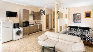 Eine moderne Wohnung mit Küchenzeile, Sofa, Bett und Fernseher.