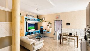 Ein Hotelzimmer mit Fernseher, Schreibtisch, Stuhl, Sofa, Waschmaschine und Bett.