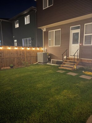A residential house with a well-maintained lawn, a wooden fence, and a front door with steps leading up to it. - Cozy 1-bedroom studio in charming Calgary with AC (Calgary)