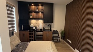 Un dormitorio con una cama, un escritorio con ordenador, una silla y una planta en maceta.
