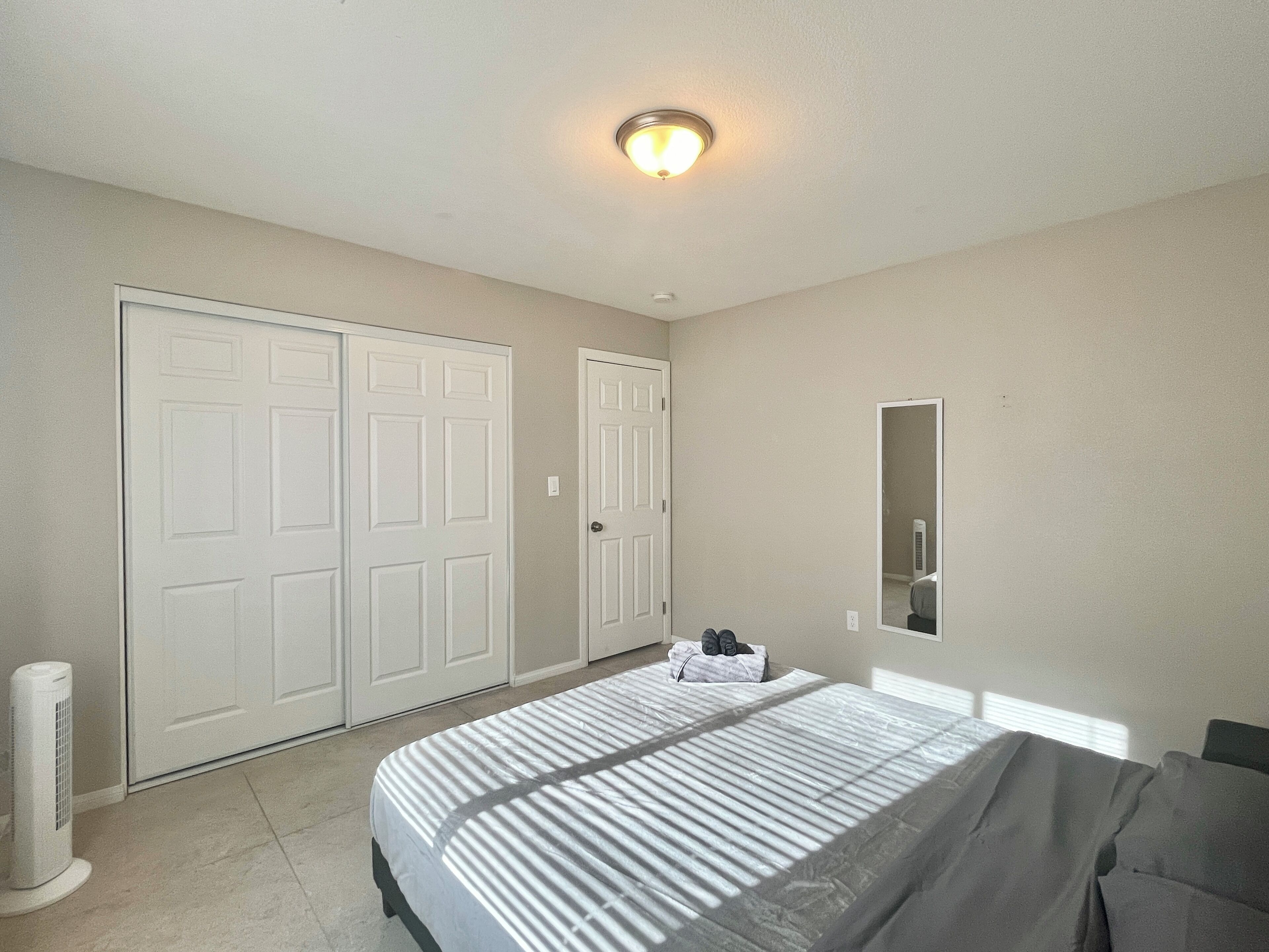 A bedroom with a bed, a heater, a wardrobe, and a mirror.