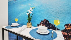 A dining table with white plates, blue placemats, a pineapple centerpiece, and a yellow drink. - Santorini - 2Bedroom/2Bath/NRG Stadium/Medical Center/Pool/Gym/Sleeps 6 (Houston)