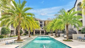 A swimming pool with palm trees, lounge chairs, and a modern building with balconies. - Santorini - 2Bedroom/2Bath/NRG Stadium/Medical Center/Pool/Gym/Sleeps 6 (Houston)