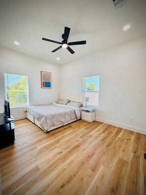 A bedroom with a bed, a desk, a ceiling fan, and two windows with blinds. - Charming 3-bedroom apartment with AC in vibrant Houston (Houston)