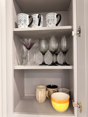 A cabinet with shelves containing various glassware and ceramic items. - Charming 3-bedroom apartment with AC in vibrant Houston (Houston)