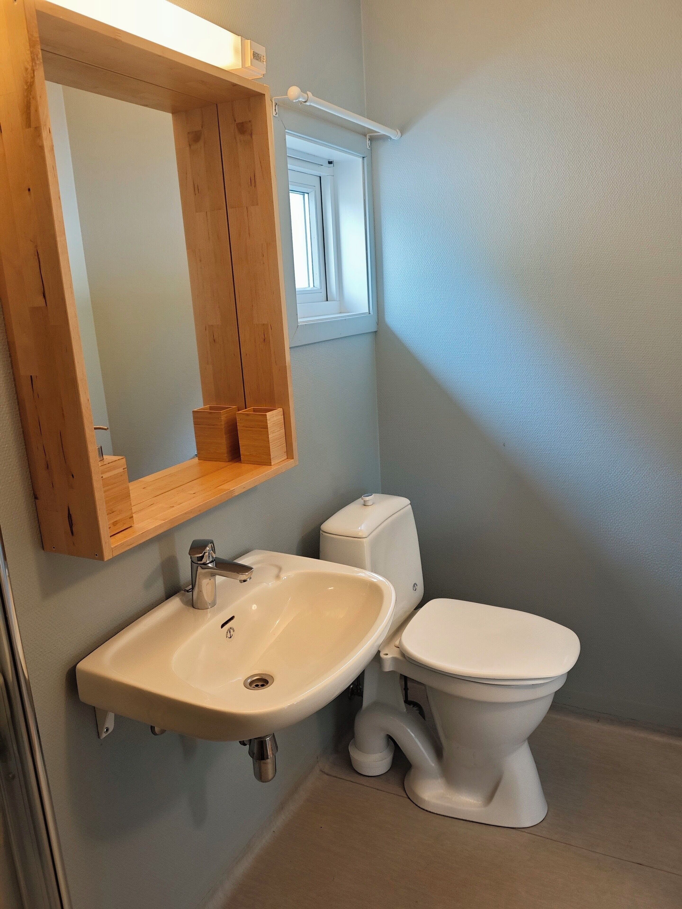 A bathroom with a wooden medicine cabinet, a sink, and a toilet.