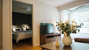 A bedroom with a bed, TV, and a vase with flowers on a table. - Norddalstunet (Norddal)