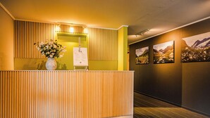 A reception desk with a wooden slat design, a vase of flowers, and a 'hi' sign. - Norddalstunet (Norddal)