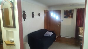 A room with a dark-colored sofa, a wooden door, a mirror, and a wall with three vases. - Mid-Century Charm Meets Modern Sparkle (Cedar Rapids)
