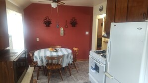 A kitchen with a round table, chairs, a stove, a refrigerator, and decorative wall pieces. - Mid-Century Charm Meets Modern Sparkle (Cedar Rapids)