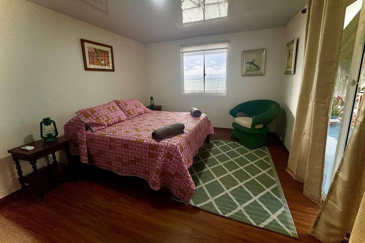 Une chambre à coucher avec un lit, une fenêtre, une chaise et une petite table.