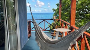 Een balkon met een hangmat, een tafel en uitzicht op de oceaan.