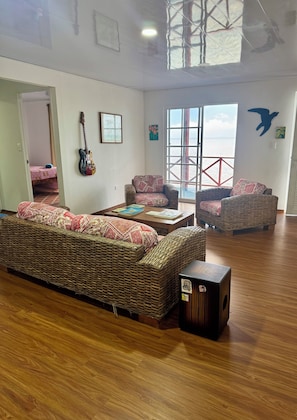 A spacious living area with wicker furniture, a large window, and a view of the outdoors.