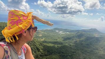 Una persona con uno zaino che ammira un paesaggio montuoso sotto un cielo sereno.
