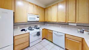 A kitchen with wooden cabinets, a white stove, a microwave, and a dishwasher. - Waterfront 2BR Condo-Walk to Iconic Seattle Spots (Seattle)