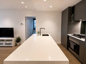 Eine moderne Küche mit Kochinsel, integriertem Fernseher und Herd.