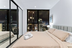 Ein modernes Hotelzimmer mit einem großen Bett, einem Nachttisch und Blick auf die Stadt.
